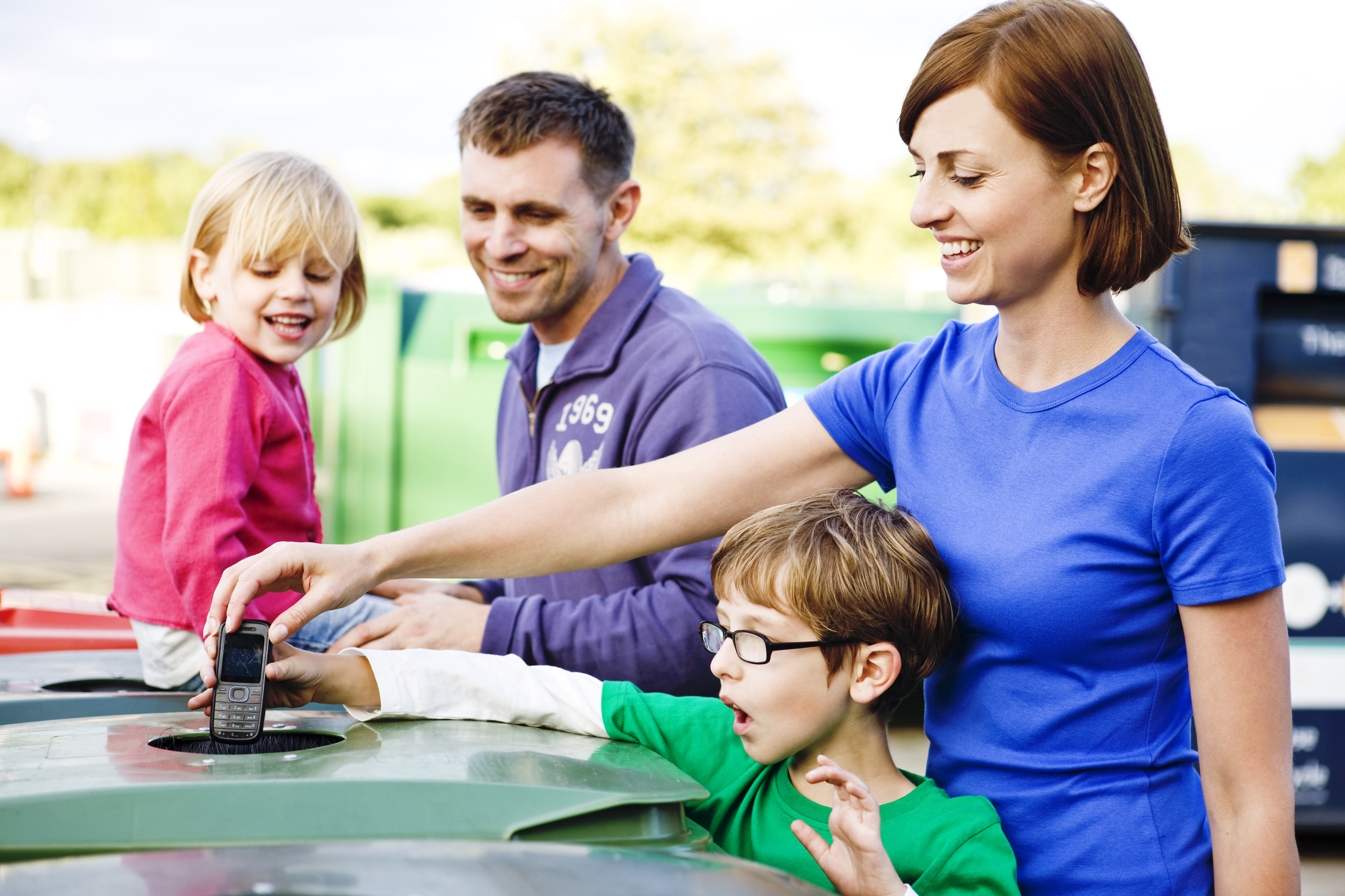 Familia depositando con hijos productos en contenedores de reciclaje